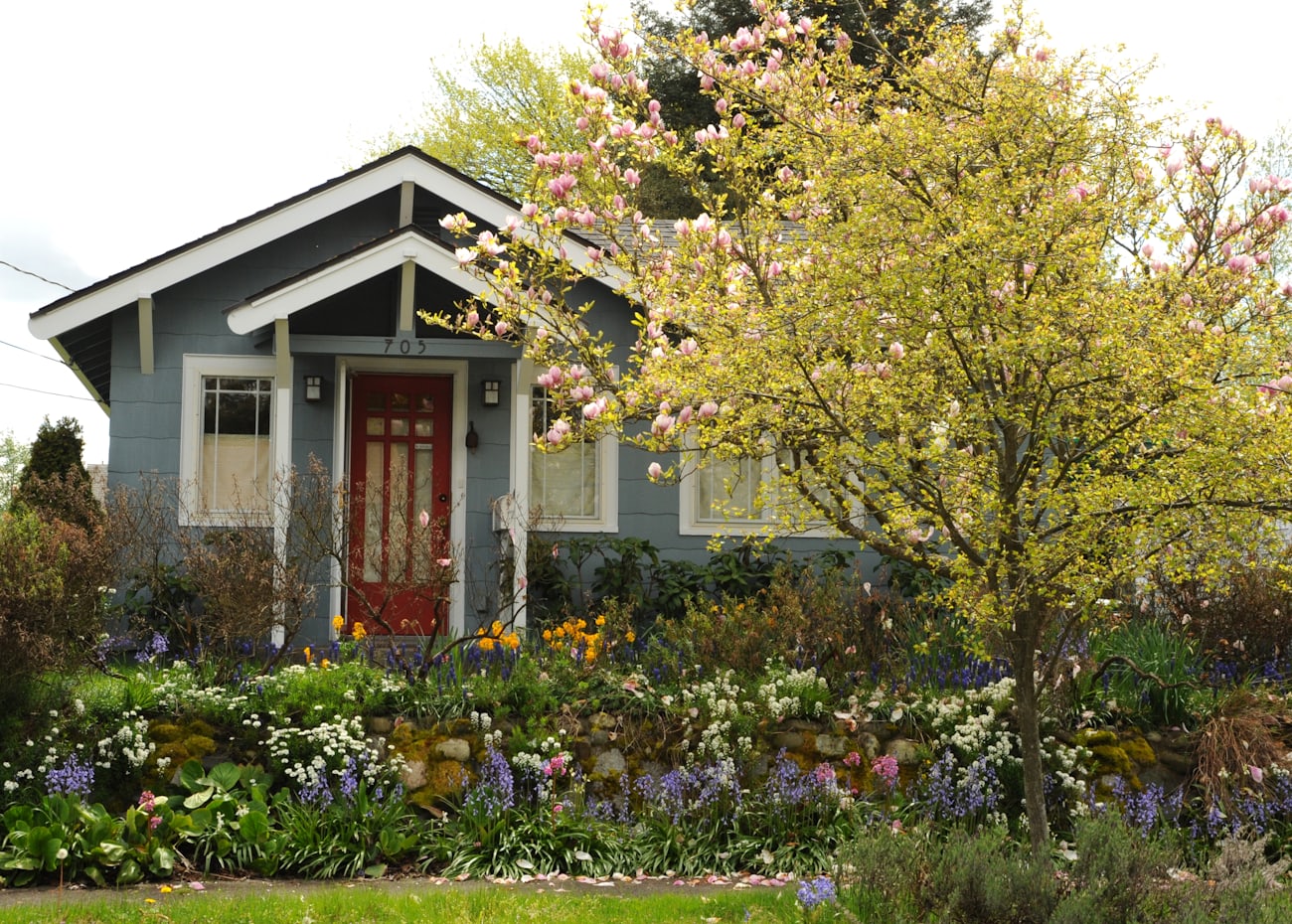 A restored Seattle craftsman bungalow with a red door and a blooming spring garden